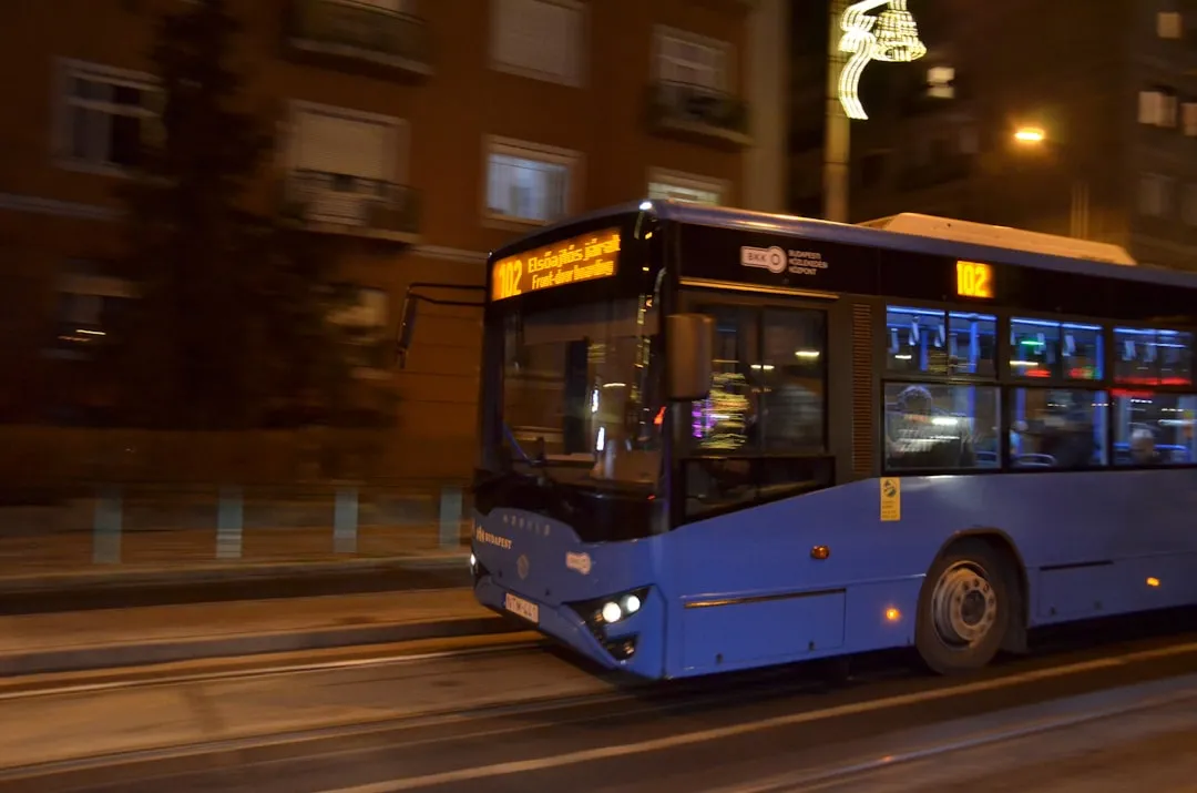 Blue bus moving on a city street at night.