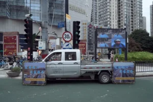 A truck driving down a street next to tall buildings