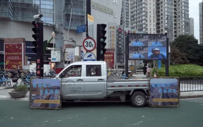 A truck driving down a street next to tall buildings