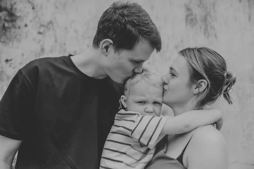 Parents kissing their young child on the head
