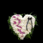 A heart-shaped floral arrangement with white and purple flowers.